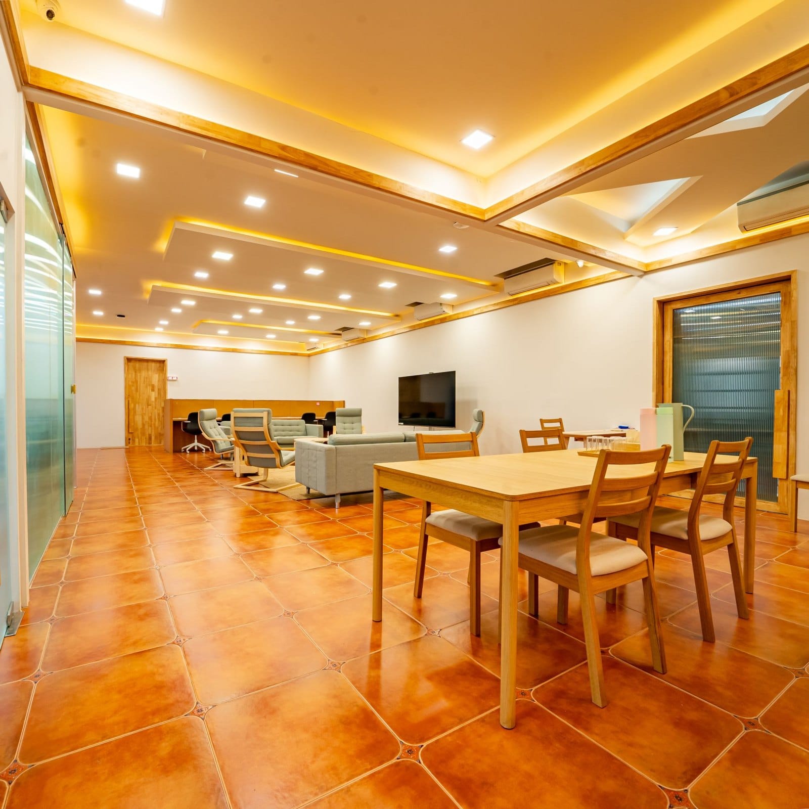 The lounge: sofas, armchairs and a dining table under warm light
